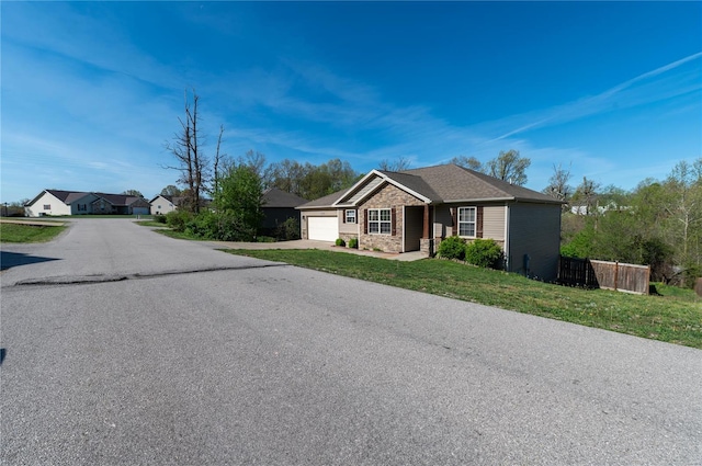 view of front of property with a front yard, driveway, a garage, and fence