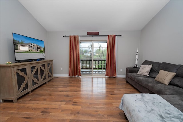 living area featuring lofted ceiling, wood finished floors, and baseboards
