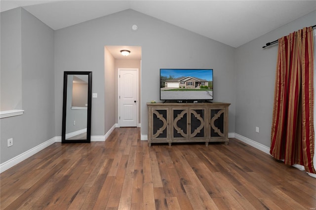 unfurnished living room with baseboards, vaulted ceiling, and wood-type flooring