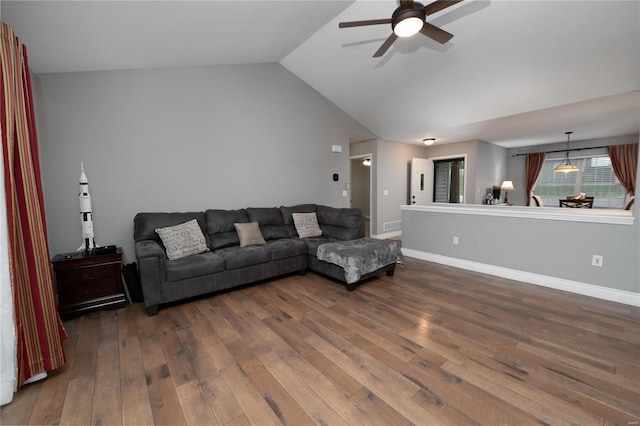 living area featuring dark wood-style floors, a ceiling fan, vaulted ceiling, and baseboards