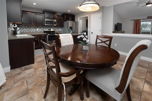 dining area featuring stone finish flooring, ceiling fan, vaulted ceiling, and baseboards