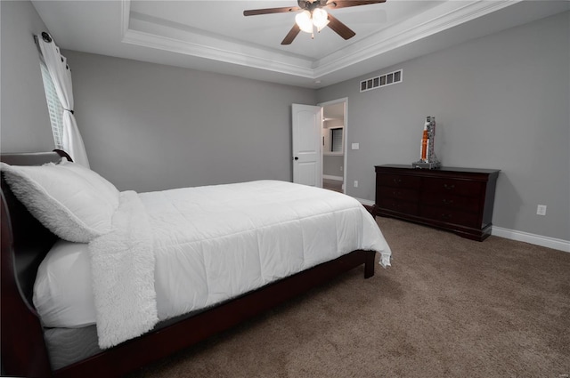 bedroom with ornamental molding, ceiling fan, carpet flooring, visible vents, and a tray ceiling