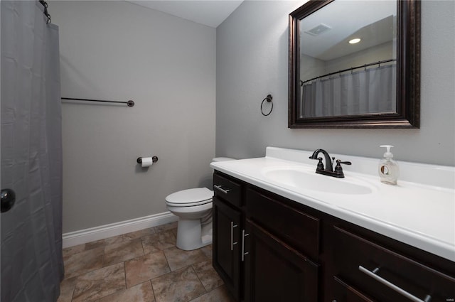 bathroom with vanity, stone finish flooring, toilet, visible vents, and baseboards