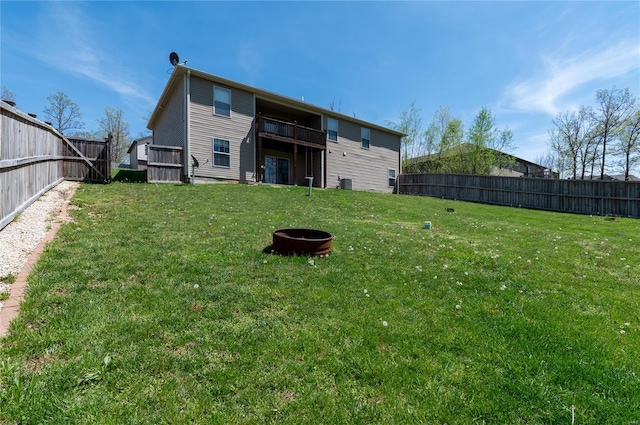rear view of house with a yard, central AC, and a fenced backyard