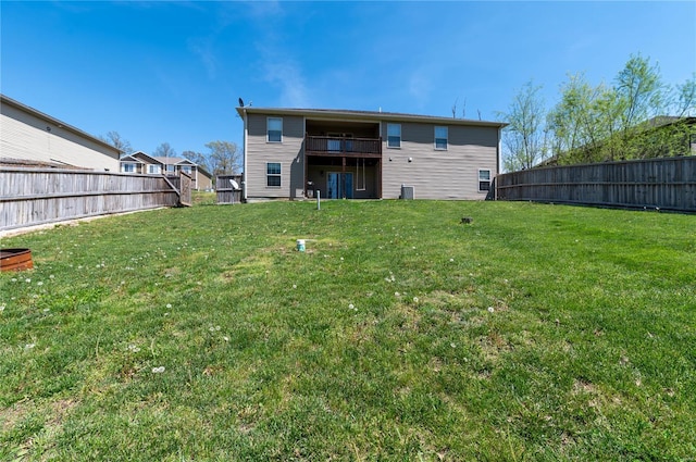 rear view of house with a fenced backyard and a lawn
