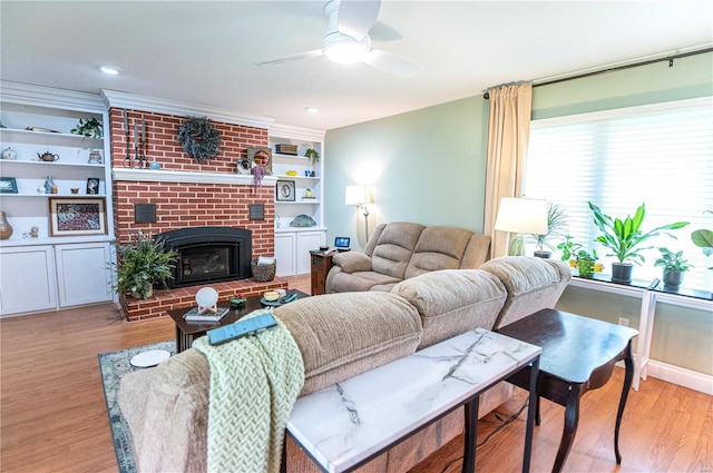 living area with ceiling fan, a fireplace, light wood-type flooring, and built in shelves