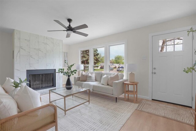 living area with baseboards, ceiling fan, wood finished floors, and a fireplace