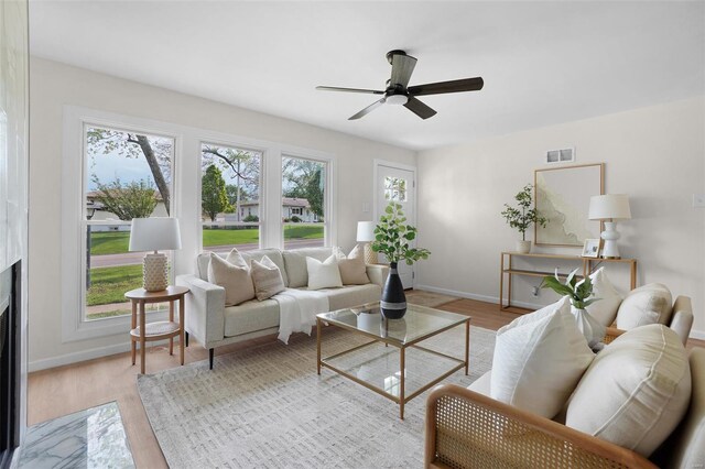 living room featuring visible vents, a ceiling fan, a fireplace with flush hearth, and wood finished floors