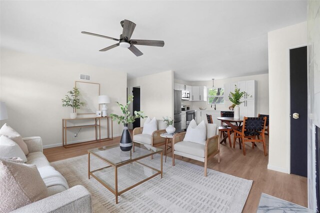 living area with ceiling fan, visible vents, baseboards, and light wood-type flooring