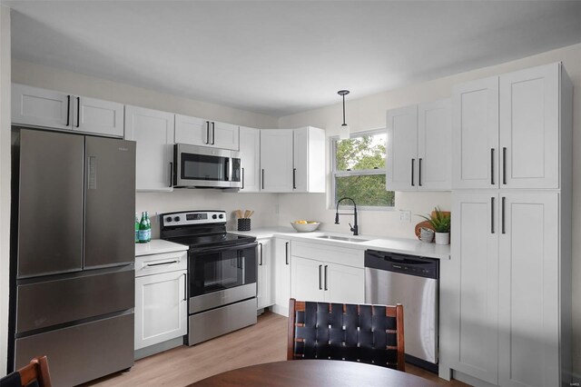 kitchen featuring light countertops, a sink, light wood-type flooring, and stainless steel appliances