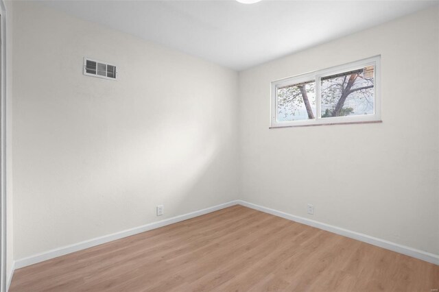unfurnished room featuring visible vents, light wood finished floors, and baseboards