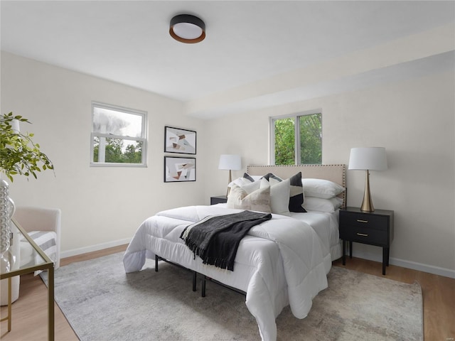 bedroom featuring baseboards, multiple windows, and wood finished floors