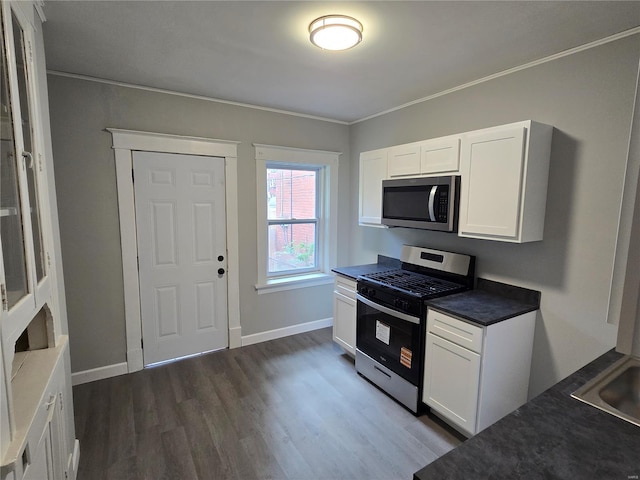 kitchen featuring ornamental molding, stainless steel appliances, white cabinets, and dark wood-style floors