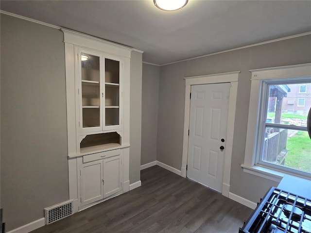 doorway to outside featuring dark wood-style flooring, visible vents, ornamental molding, and baseboards