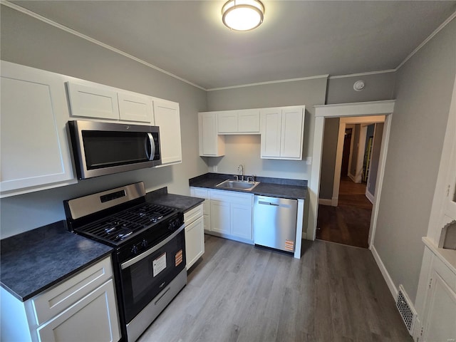 kitchen featuring white cabinetry, a sink, visible vents, stainless steel appliances, and light wood-type flooring