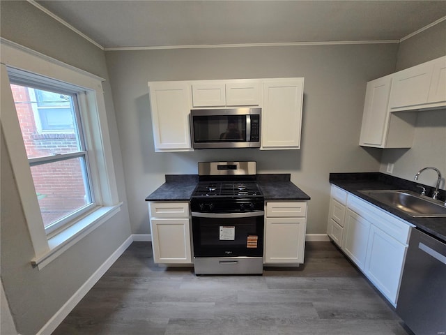 kitchen with white cabinetry, crown molding, light wood-style flooring, a sink, and stainless steel appliances
