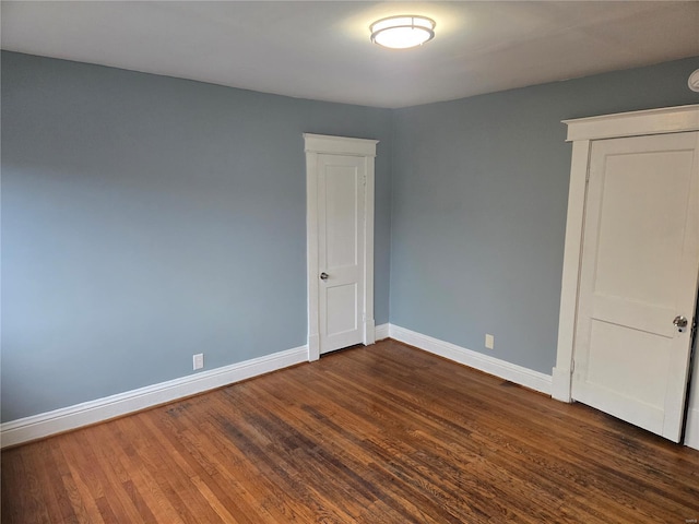 empty room with dark wood finished floors and baseboards