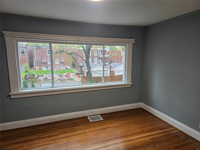 empty room with visible vents, dark wood-style floors, and baseboards