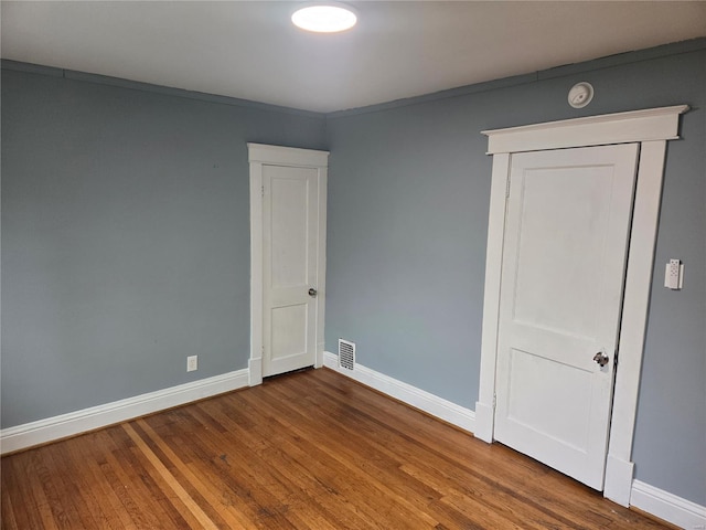 spare room with baseboards, visible vents, and wood finished floors