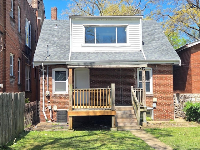 view of front of house featuring brick siding, fence, and a shingled roof