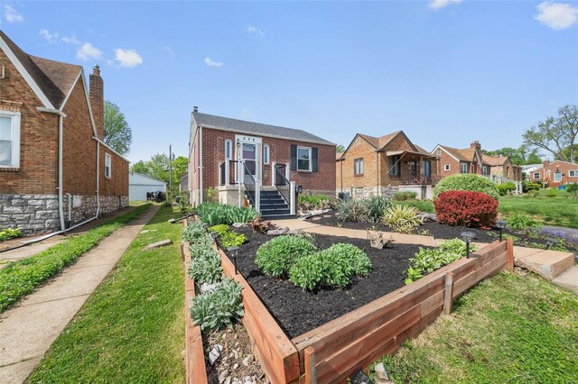 view of front facade with a residential view, a front lawn, a vegetable garden, and brick siding