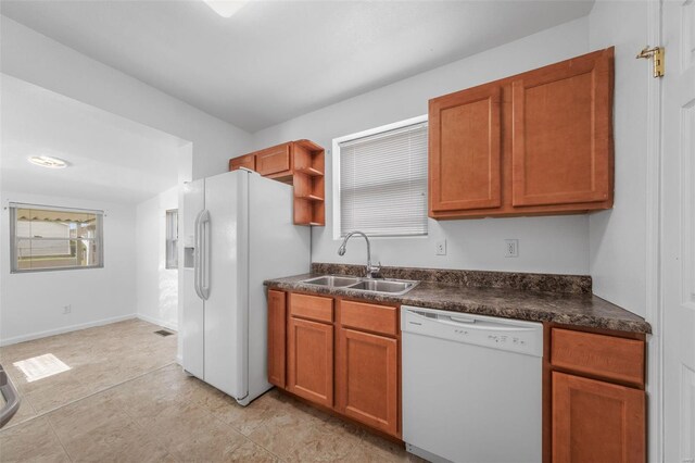 kitchen featuring dark countertops, open shelves, brown cabinets, a sink, and white appliances