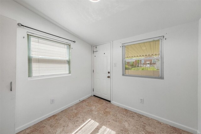 unfurnished room featuring baseboards and lofted ceiling