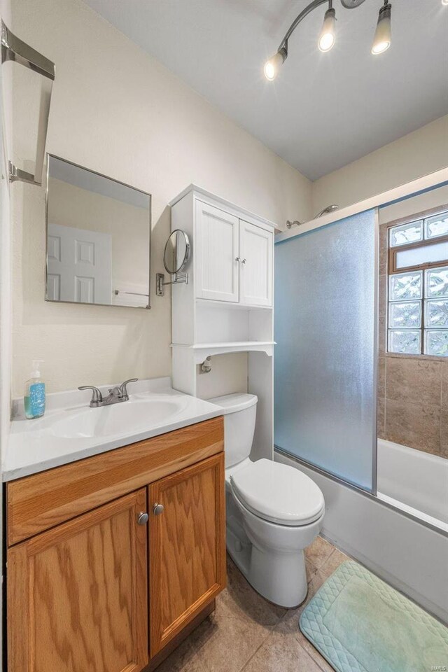 full bath with vanity, enclosed tub / shower combo, tile patterned floors, and toilet