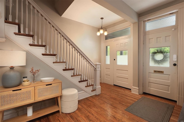 entryway with stairway, an inviting chandelier, and wood finished floors