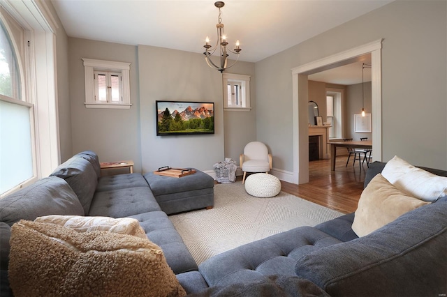 living area featuring baseboards, wood finished floors, and a notable chandelier