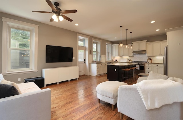 living room with recessed lighting, ceiling fan, and light wood-style flooring