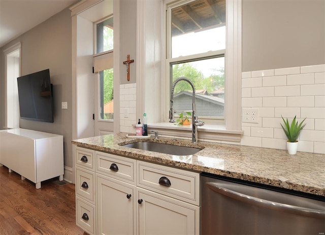 kitchen with decorative backsplash, light stone counters, a sink, dark wood finished floors, and dishwasher