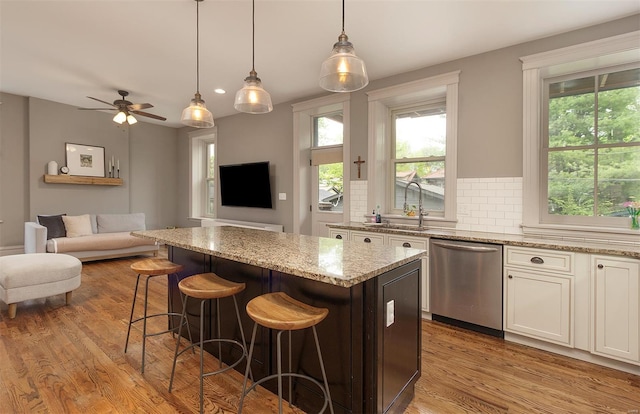 kitchen featuring stainless steel dishwasher, open floor plan, a kitchen island, and wood finished floors