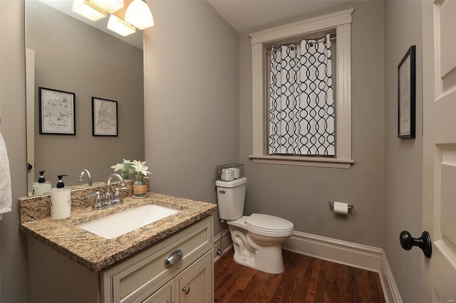 bathroom featuring baseboards, vanity, toilet, and wood finished floors