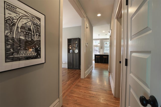 corridor with baseboards, recessed lighting, and wood finished floors