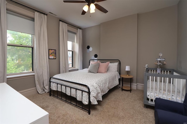 bedroom featuring visible vents, multiple windows, and light carpet