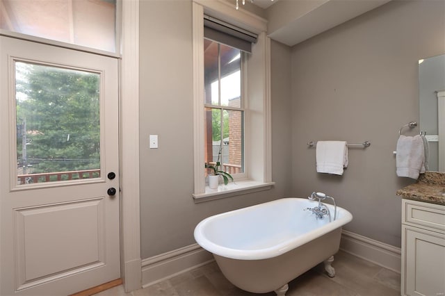 full bath with a freestanding tub, baseboards, and vanity
