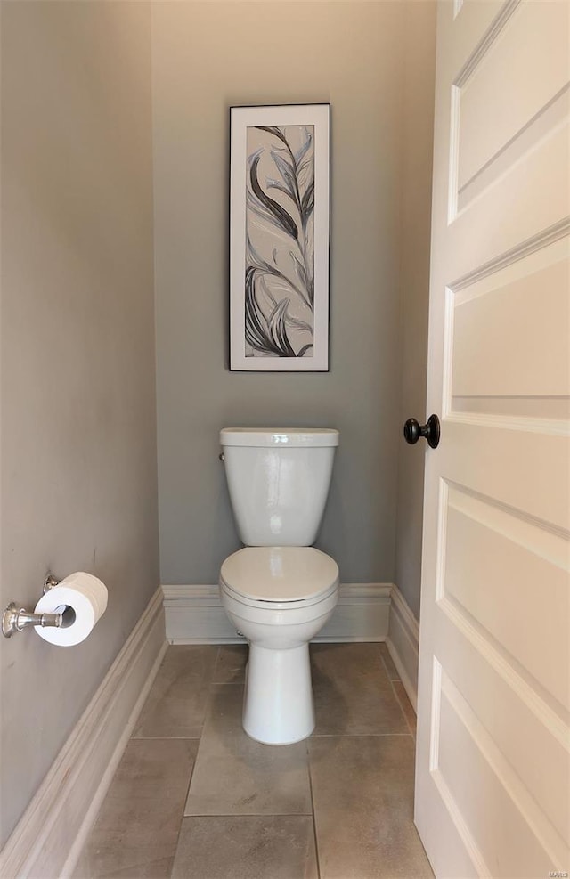 bathroom with toilet, baseboards, and tile patterned flooring