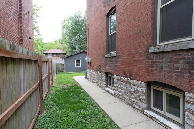 view of side of home with a lawn, fence, and brick siding