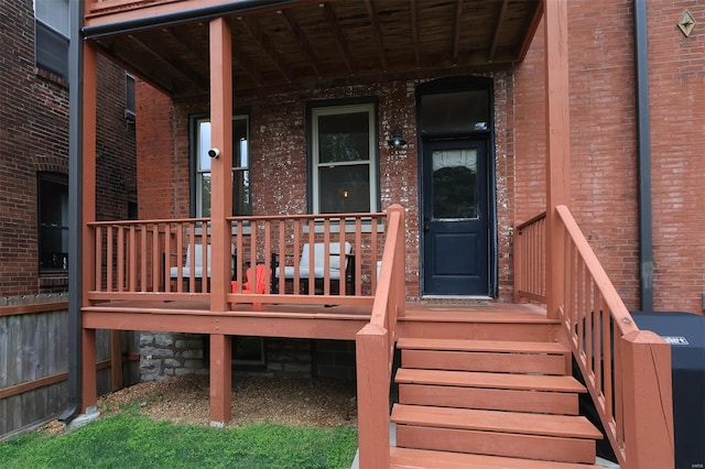 entrance to property featuring a porch and brick siding