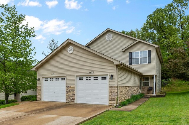 view of front of house with an attached garage, concrete driveway, a front lawn, and stone siding