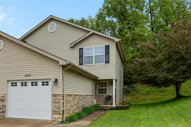 view of front facade featuring an attached garage, stone siding, a front yard, and concrete driveway
