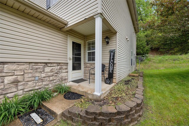 doorway to property featuring a lawn and stone siding