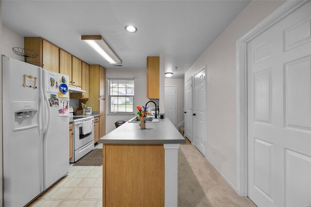 kitchen featuring brown cabinetry, a peninsula, white appliances, under cabinet range hood, and a sink