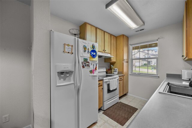 kitchen featuring visible vents, white appliances, light floors, under cabinet range hood, and a sink