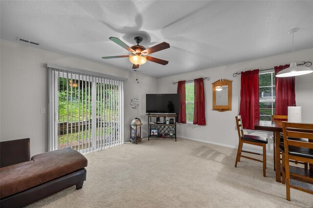 living room featuring visible vents, carpet floors, baseboards, ceiling fan, and a textured ceiling