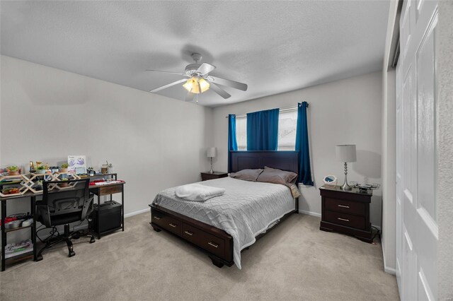 bedroom featuring a ceiling fan, light carpet, a closet, and a textured ceiling