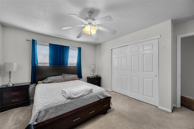 bedroom featuring light carpet, a textured ceiling, a ceiling fan, baseboards, and a closet
