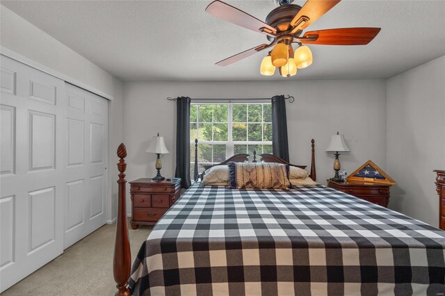 bedroom with a closet, a textured ceiling, ceiling fan, and light carpet