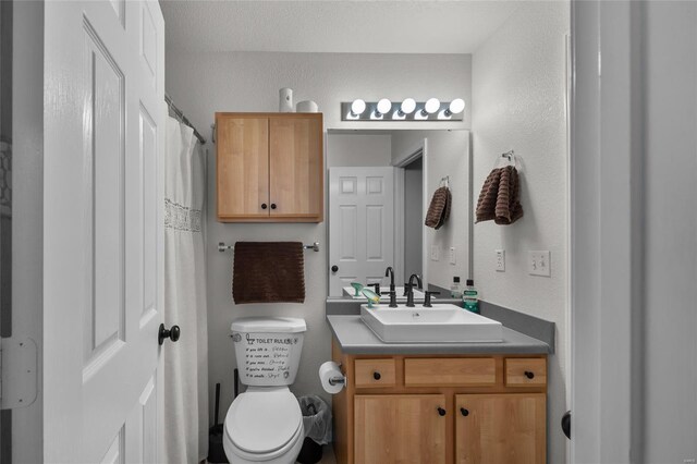 bathroom with vanity, a textured wall, and toilet